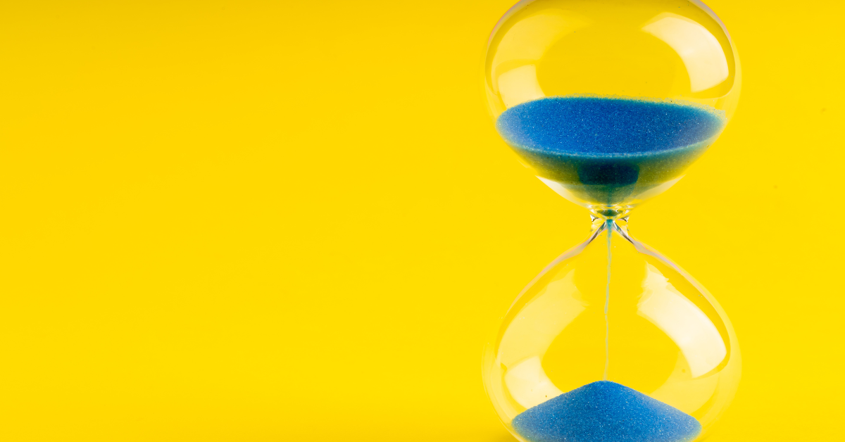 Hourglass with blue sand on a yellow background symbolising visa time running out in the UK.
